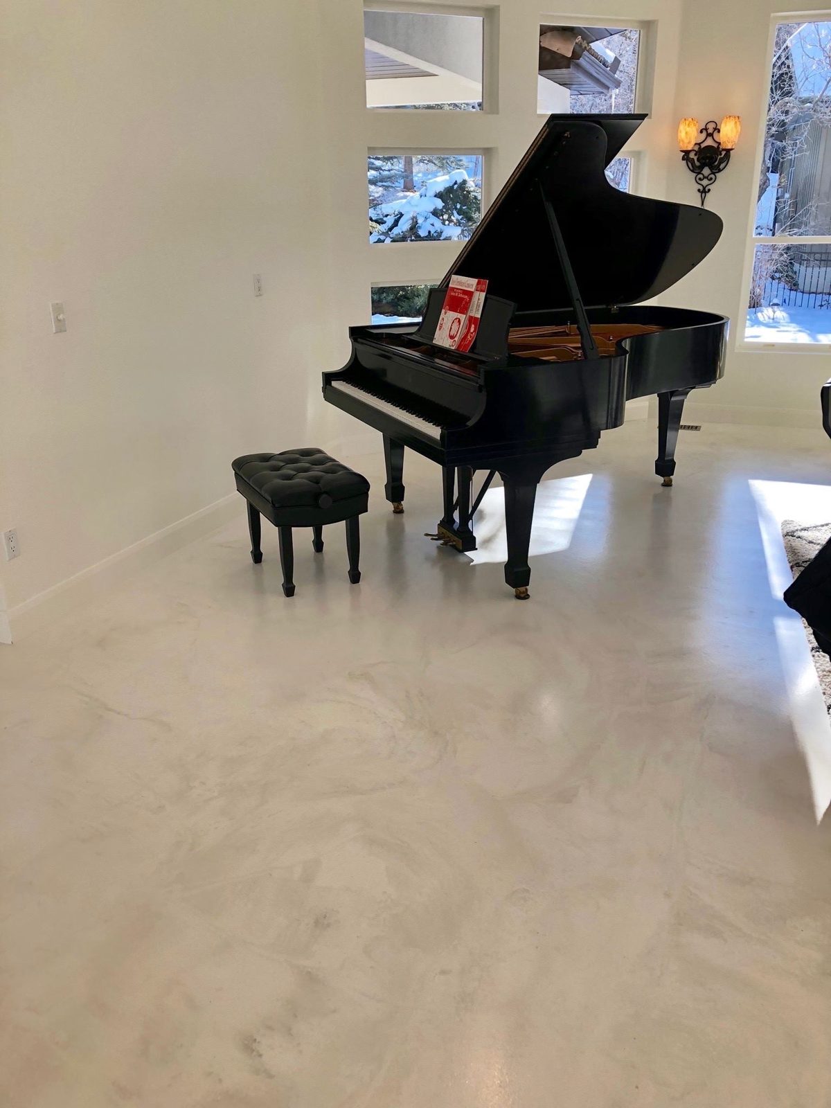 Marble-look microcement floor across an open living space with grand piano — Nashville