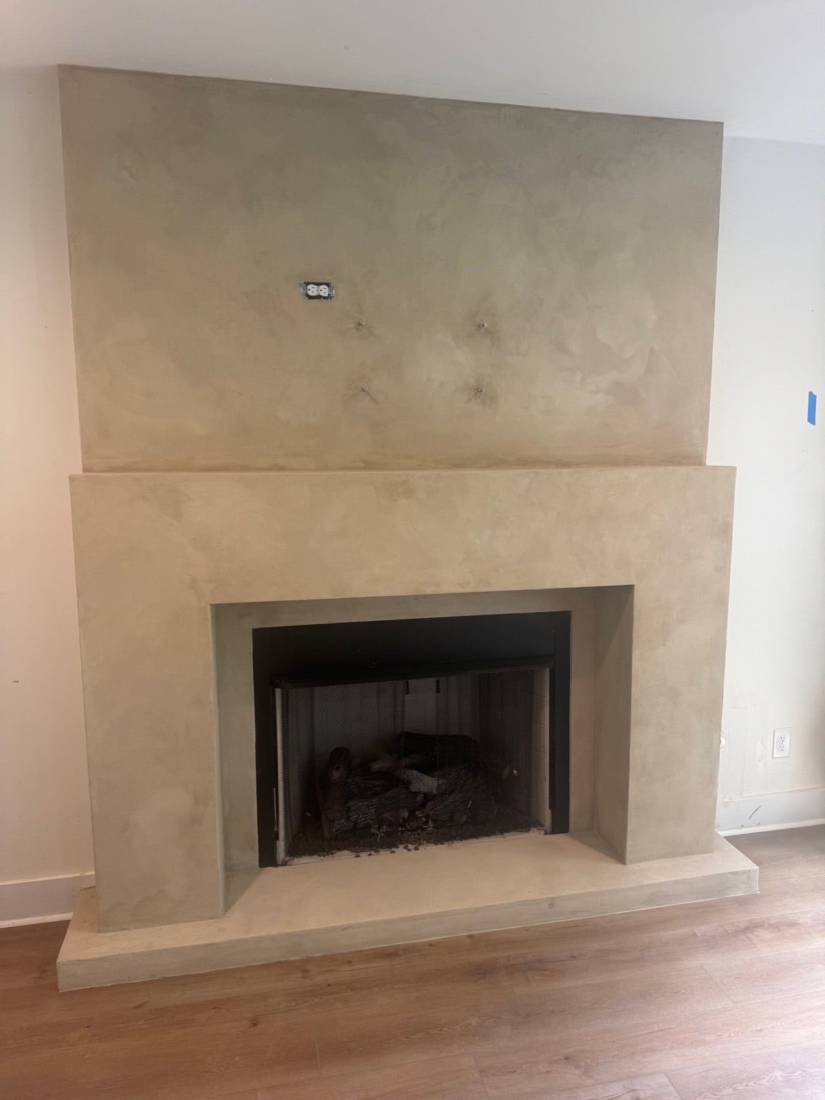 Velluto microcement fireplace in Franklin, a warm cream surround running from the floating hearth to the ceiling in one unbroken plane
