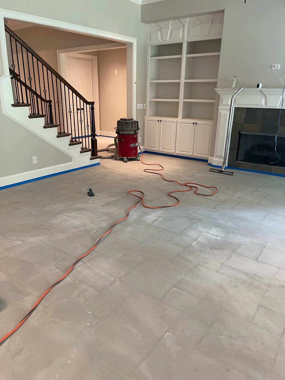 The same Brentwood great room before the microcement, the original travertine tile masked off at the baseboards on the first day of work